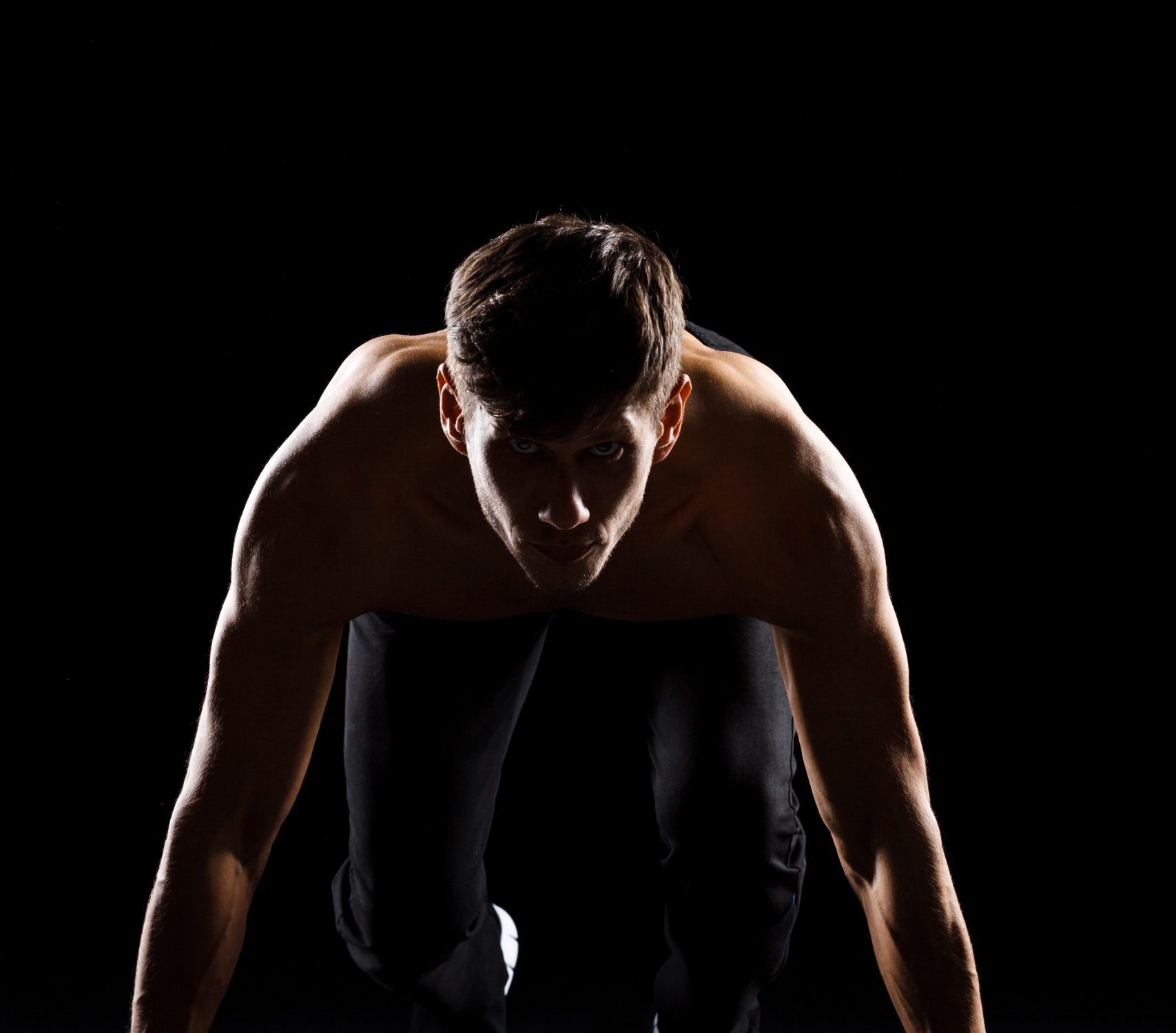 Athlete prepare to run over black background Athlete prepare to run over black background, looking at camera